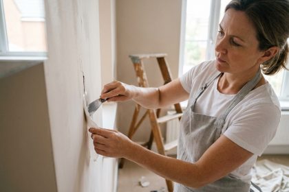 Femme appliquant du moulage sur une fissure murale dans un salon, travaux de rénovation maison simples et accessibles