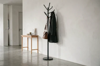 Porte manteaux moderne en métal noir mat dans une entrée minimaliste avec sol en béton poli et console en chêne
